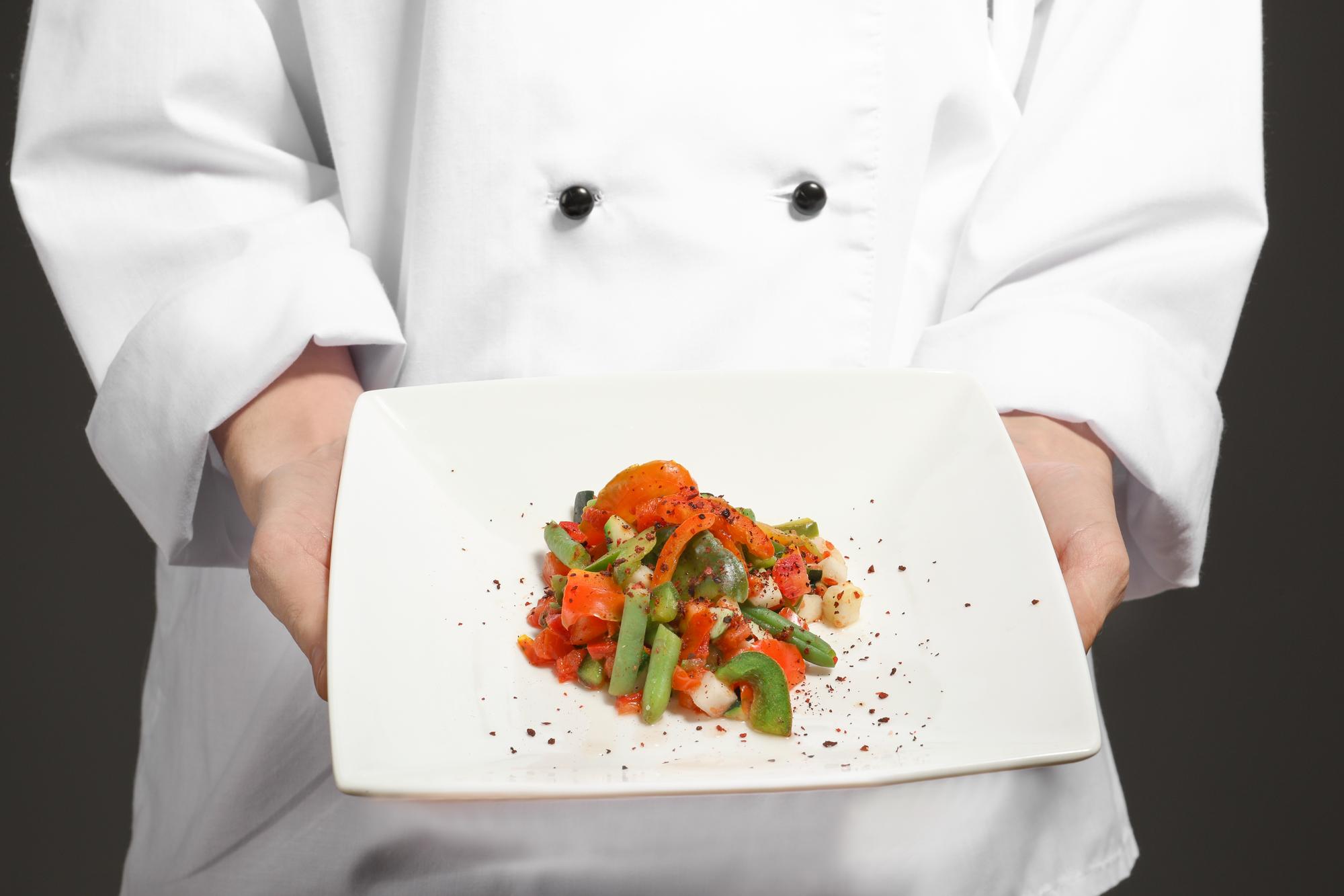 Chef showing a plated dish in a modern kitchen